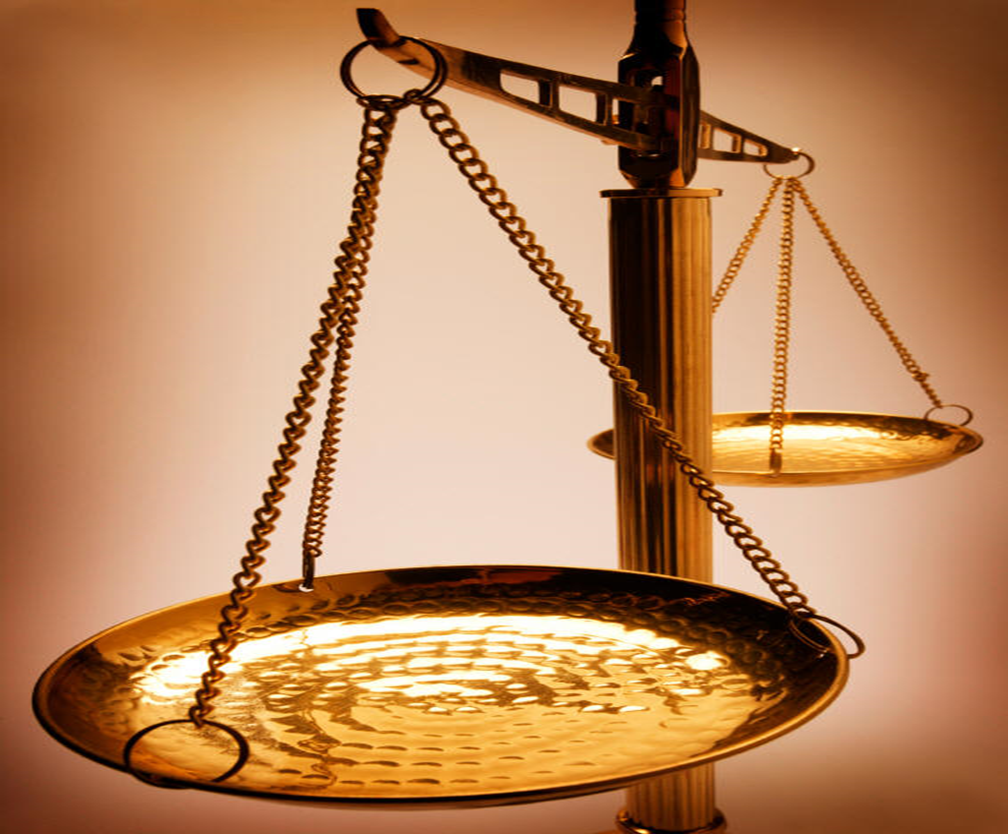 Close-up of a golden balance scale with one pan in the foreground and another in the background against a warm, softly lit backdrop.